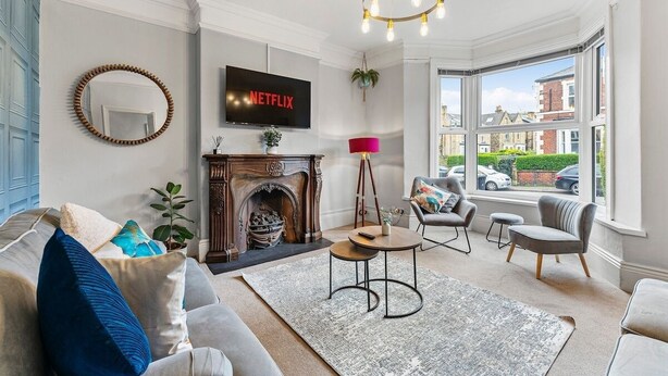 Ein Wohnzimmer mit Kamin, einem an der Wand montierten Fernseher und einem großen Fenster mit Blick ins Freie.