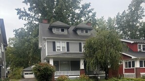 A two-story residential house with a front porch, a garage, and a well-maintained lawn.