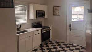A kitchen with white cabinets, a microwave, an oven, and a sink.