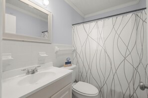 A bathroom with a white sink, mirror, and toilet.