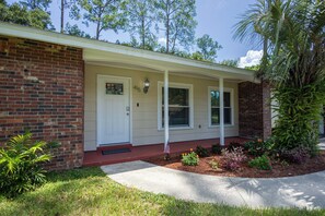 A two-story house with a brick facade, a white front door, and a covered porch.