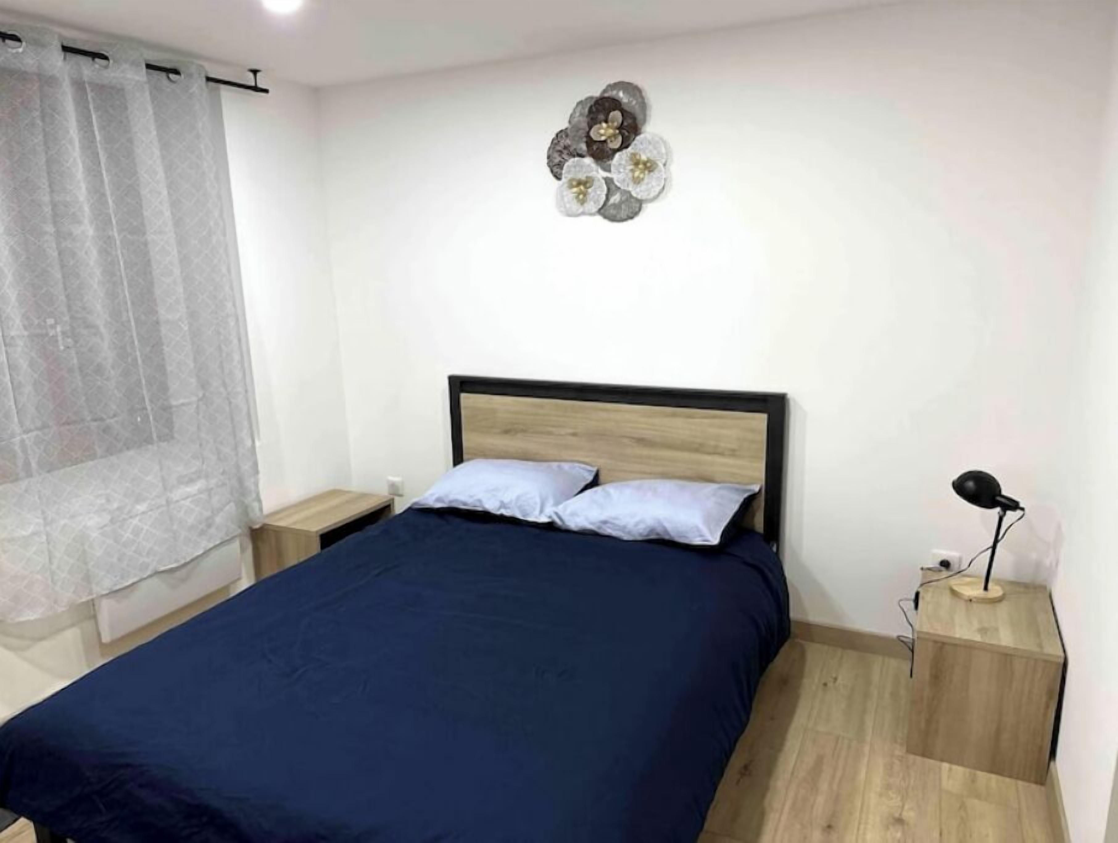 Ein Schlafzimmer mit einem Bett, zwei Nachttischen, einer Lampe und einem Wanddekor.