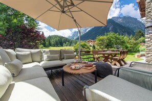 An outdoor seating area with a wooden table, cushioned chairs, and a large umbrella.
