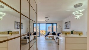 A spacious living area with a sofa set, a coffee table, and a dining table with chairs. There are large windows offering a view of the outside. - Charming Villa Mirador del Duque (Costa Adeje)