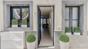 A modern building entrance with a clear pathway, potted plants, and a visible interior hallway. - Charming Villa Mirador del Duque (Costa Adeje)