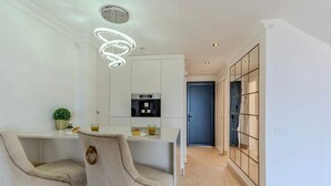 A modern kitchen with white cabinetry, a built-in oven, and a stainless steel range hood. - Charming Villa Mirador del Duque (Costa Adeje)