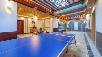 En rummelig stue med et pingpongbord, træbjælker i loftet og et ovenlysvindue.