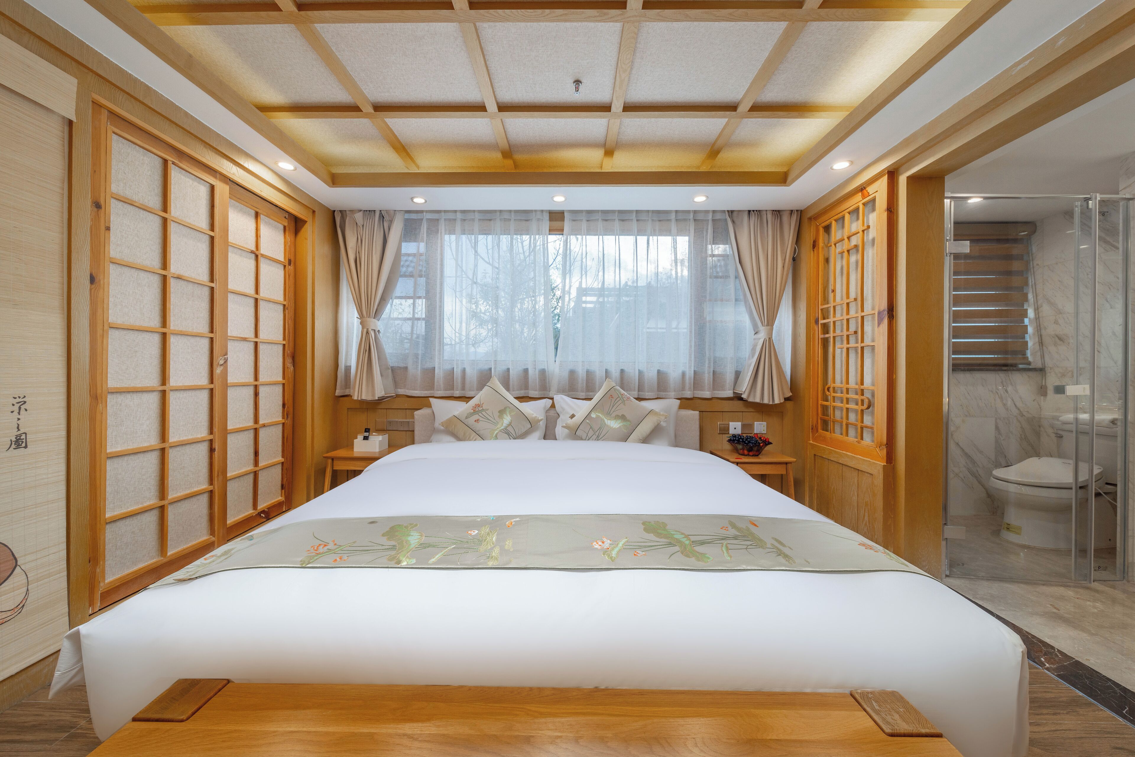 A traditional Japanese-style bedroom with a large bed, sliding doors, and a modern bathroom.