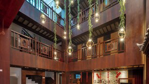 A spacious lobby with a high ceiling, wooden railings, and hanging lights. - Cloudhaven Retreat (花开花落半山居) (Lijiang)