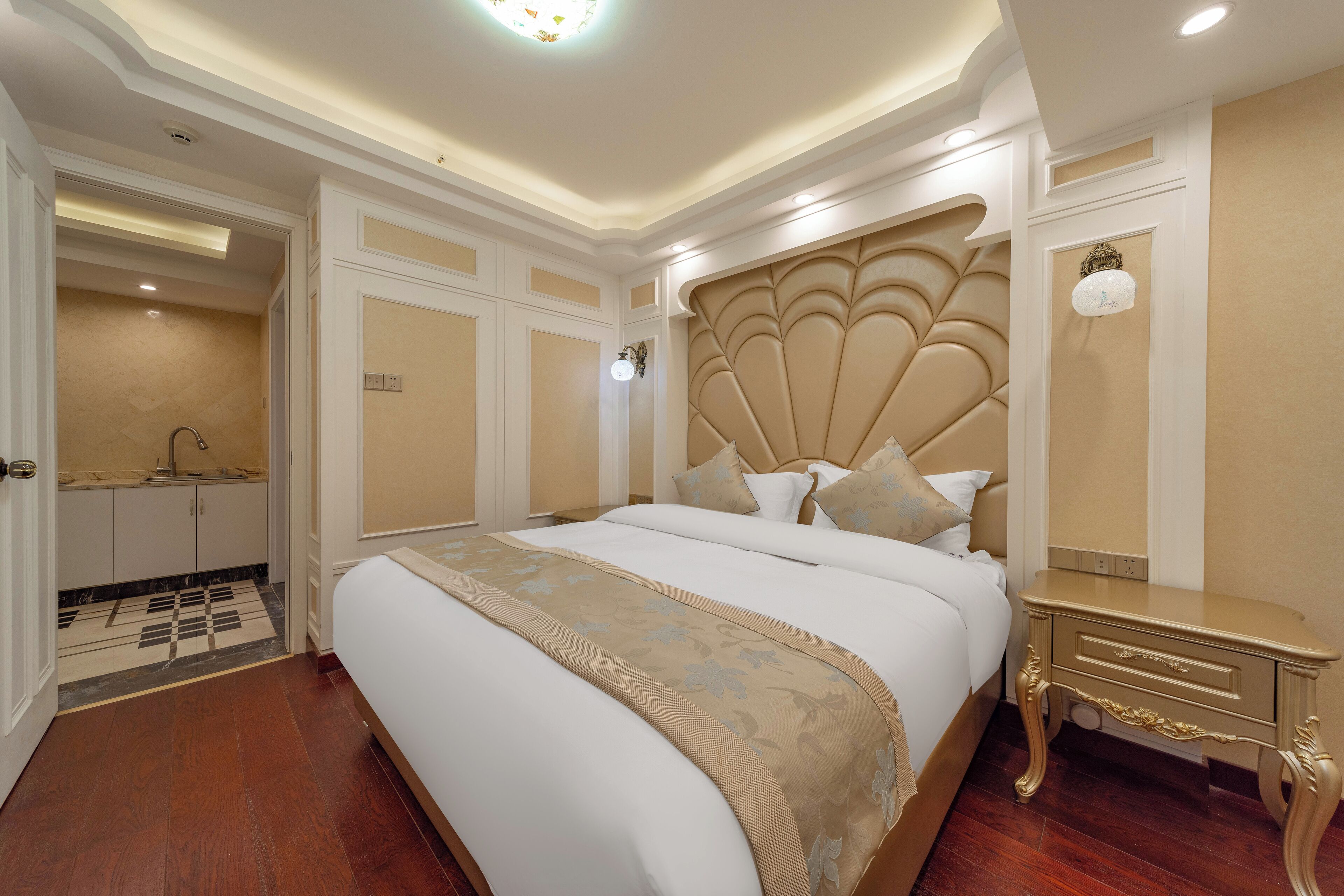 Een ruime slaapkamer met een groot bed, een kaptafel met spiegel en een decoratief hoofdeinde.