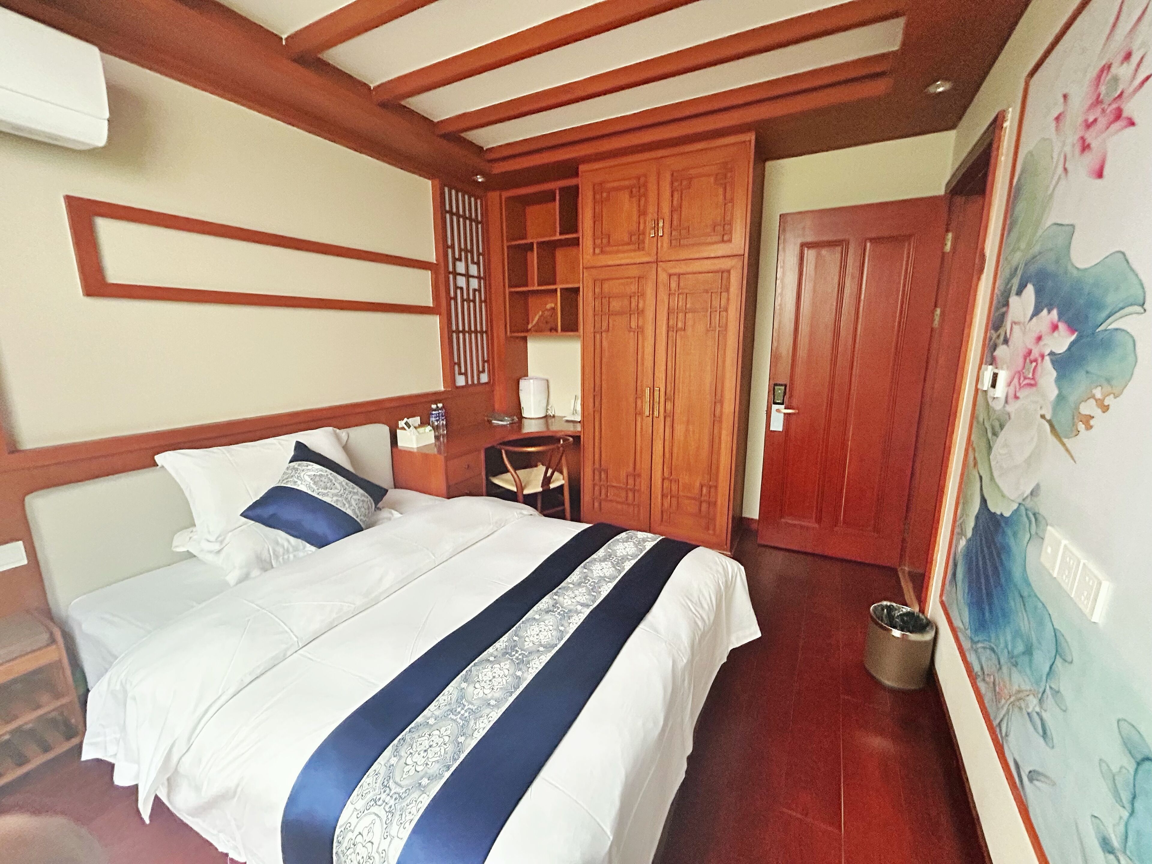 Ein Hotelzimmer mit einem Bett, einem Holzschrank, einem Schreibtisch, einem Stuhl und einem Bild an der Wand.