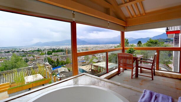 A balcony with a view of a cityscape and mountains. - Cloudhaven Retreat (花开花落半山居) (Lijiang)