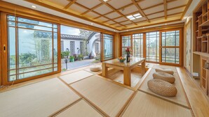 A traditional Japanese room with tatami flooring, a low wooden table, and large sliding doors. - Cloudhaven Retreat (花开花落半山居) (Lijiang)