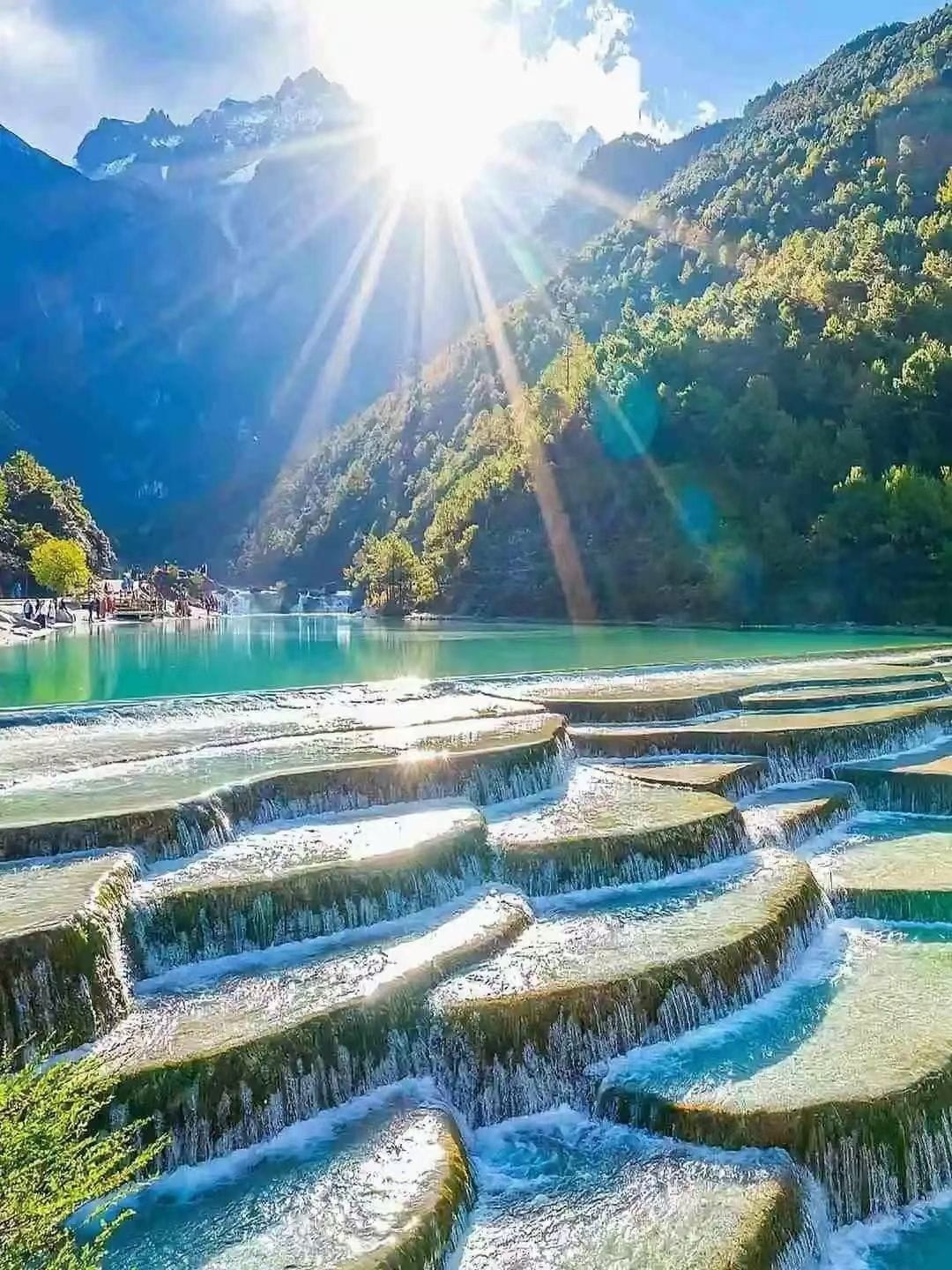 Terraced water features and a mountainous landscape with a clear sky.