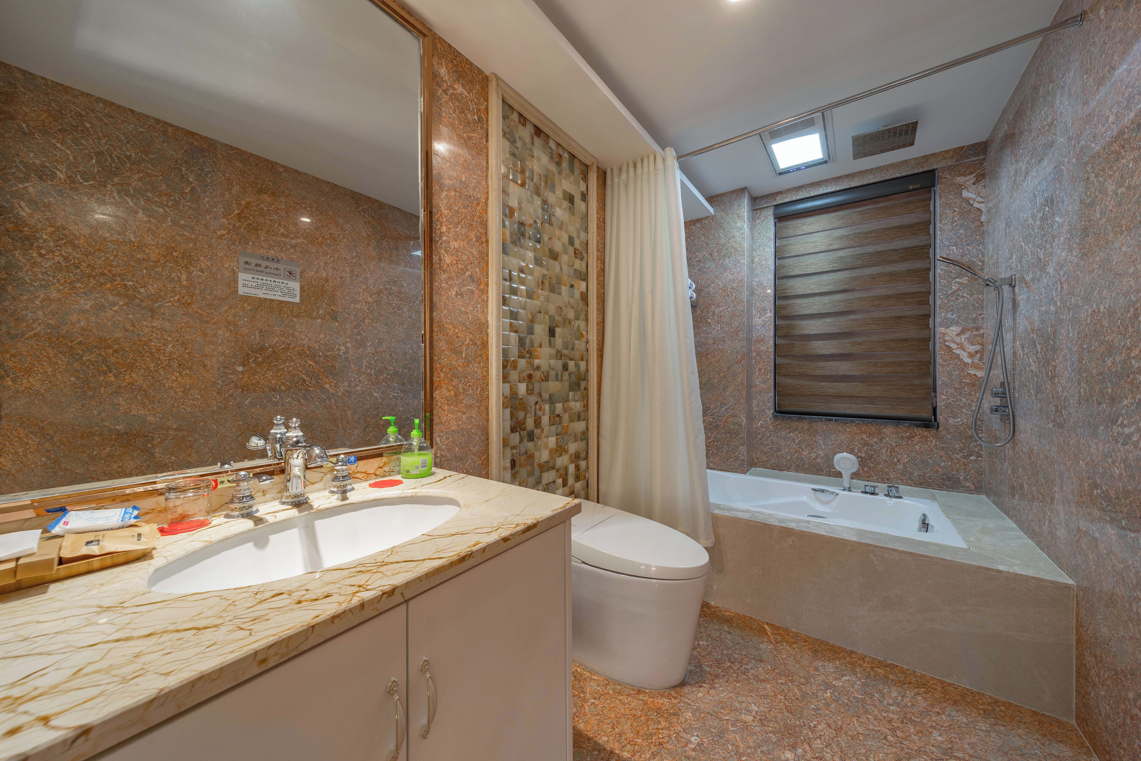 Un baño con encimera de mármol, lavamanos, inodoro y bañera.