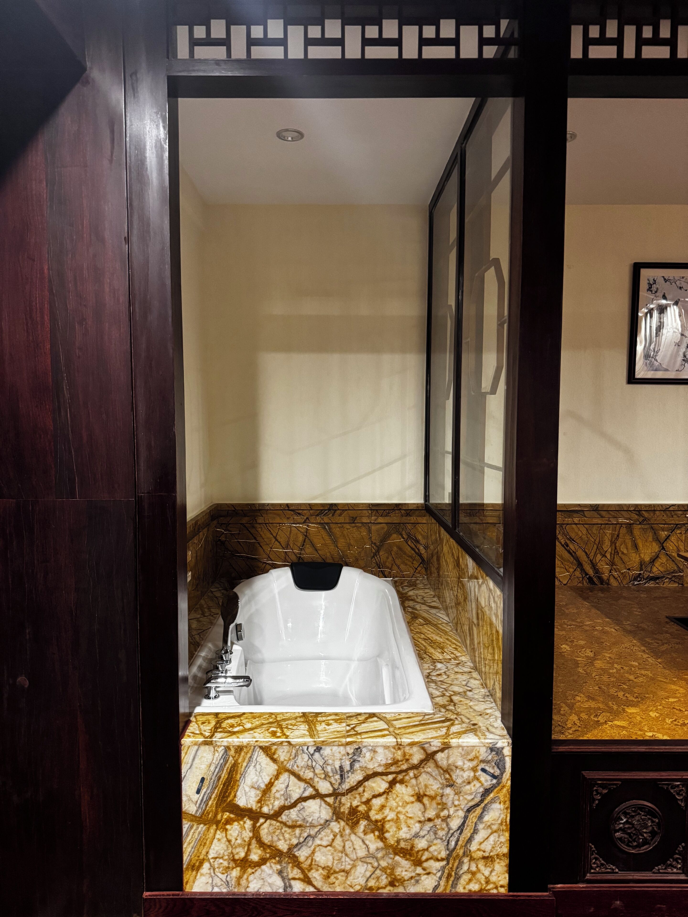 Un baño con lavamanos de mármol, un espejo y un cuadro en la pared.