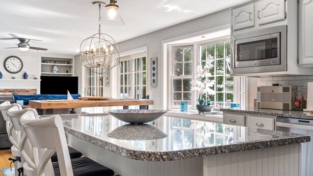 A modern kitchen with a large island, white cabinetry, and a built-in microwave. - Maine Adventure 3BR Oasis Awaits! (York)