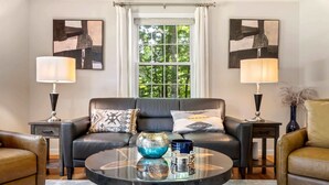A modern living room with a leather sofa, two side tables, a glass coffee table, and two lamps. - Maine Adventure 3BR Oasis Awaits! (York)