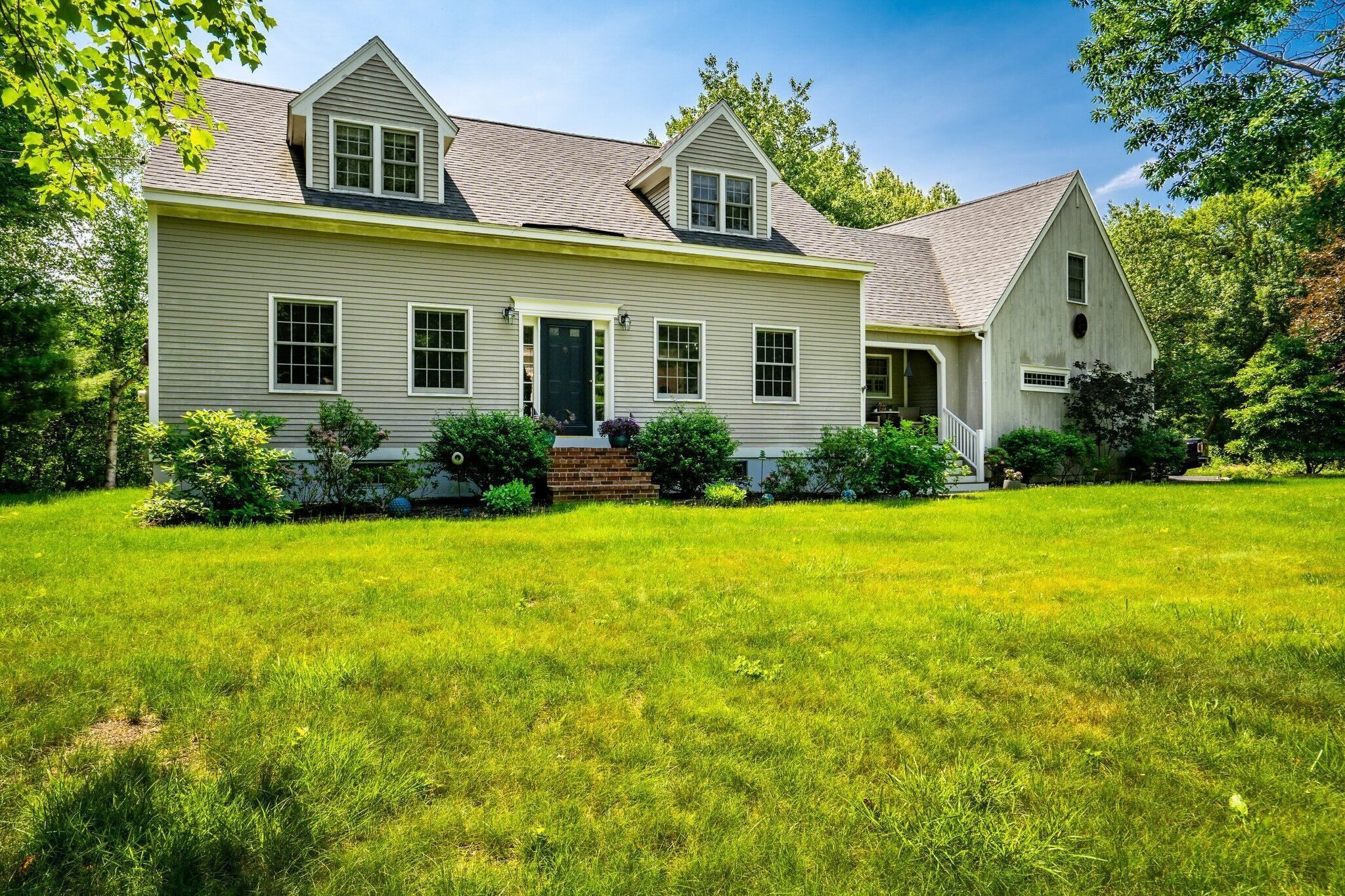 A two-story house with a front porch, a brick foundation, and a well-maintained lawn.