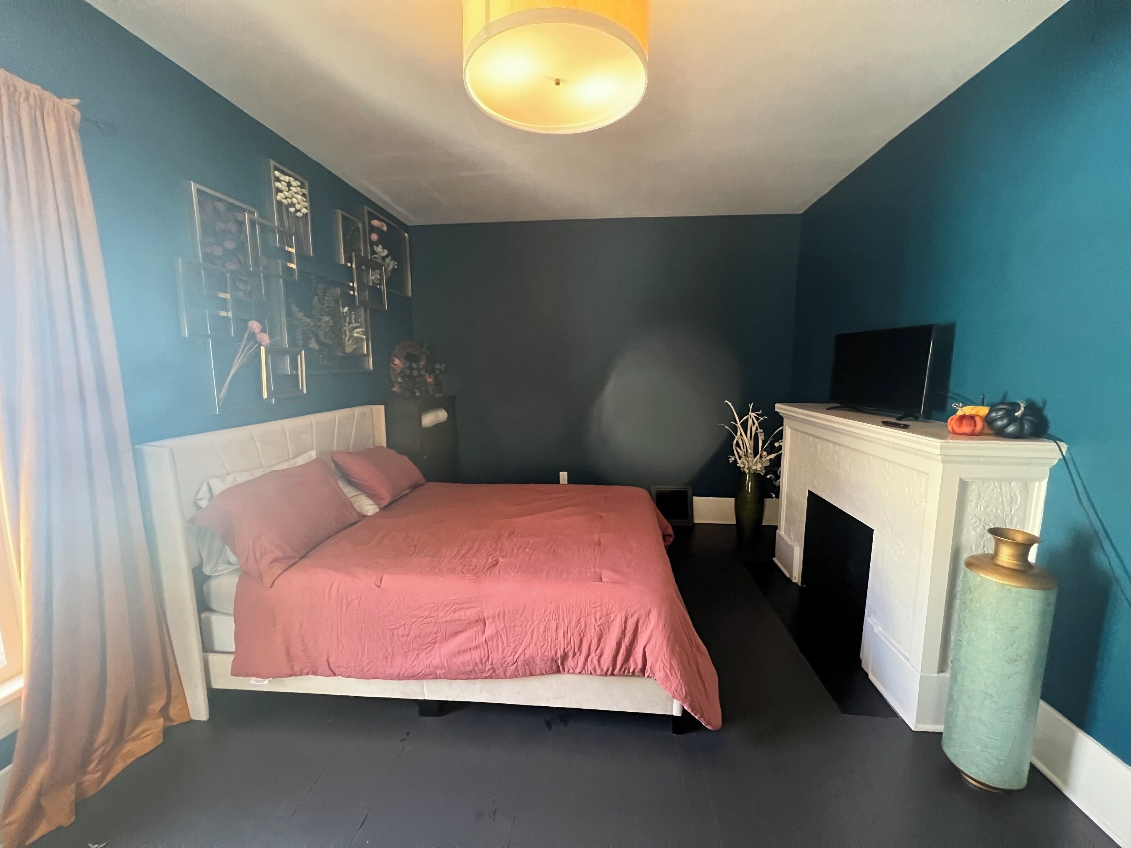Ein Schlafzimmer mit Bett, Kamin, Fernseher und einer Wand mit gerahmten Bildern.