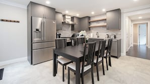 Una cocina moderna con una isla central, electrodomésticos de acero inoxidable y una zona de comedor con muebles de madera oscura.