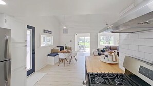 Una cocina moderna con una isla central, un comedor con mesa y sillas, y una sala de estar con sofá y mesa de centro.
