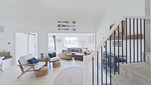 Amplia sala de estar con escaleras, piso de madera y chimenea.