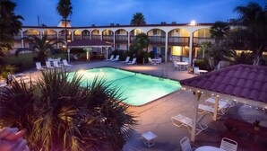 Un hôtel doté d’une piscine, de chaises longues et d’un patio couvert.