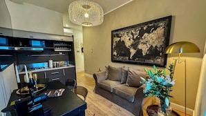 Un salón moderno con un mueble de entretenimiento negro, un sofá gris, una obra de arte con un mapa mundial, una lámpara colgante y una lámpara de pie.