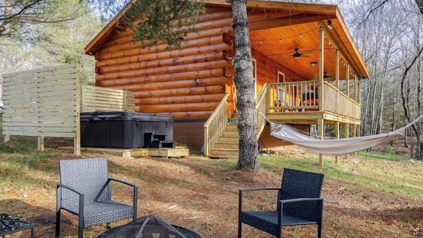 A log cabin with a porch, outdoor seating, and a hammock.