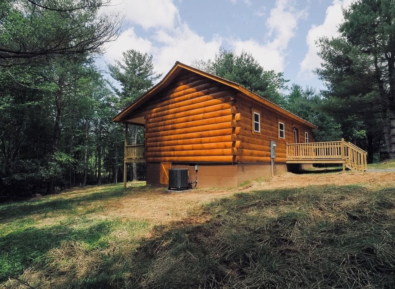 Eine Blockhütte mit einer Holzdielen-Terrasse und einer kleinen Veranda.
