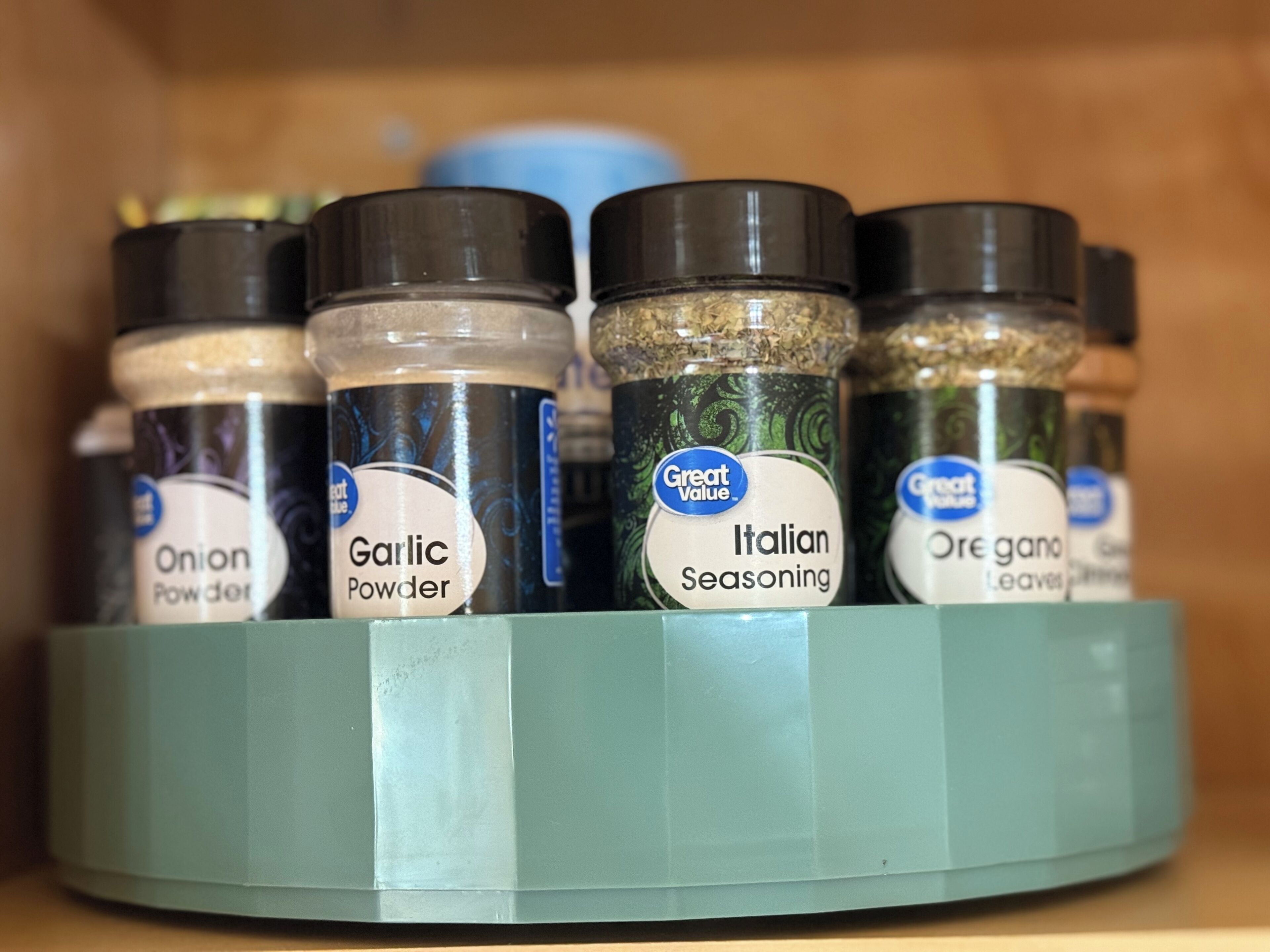 A spice rack with containers labeled 'Onion Powder', 'Garlic Powder', 'Italian Seasoning', and 'Oregano Leaves'.