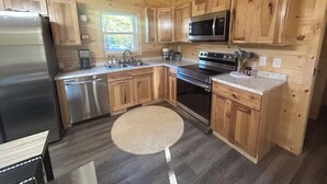 A kitchen with wooden cabinets, stainless steel appliances, a microwave, and a round rug.