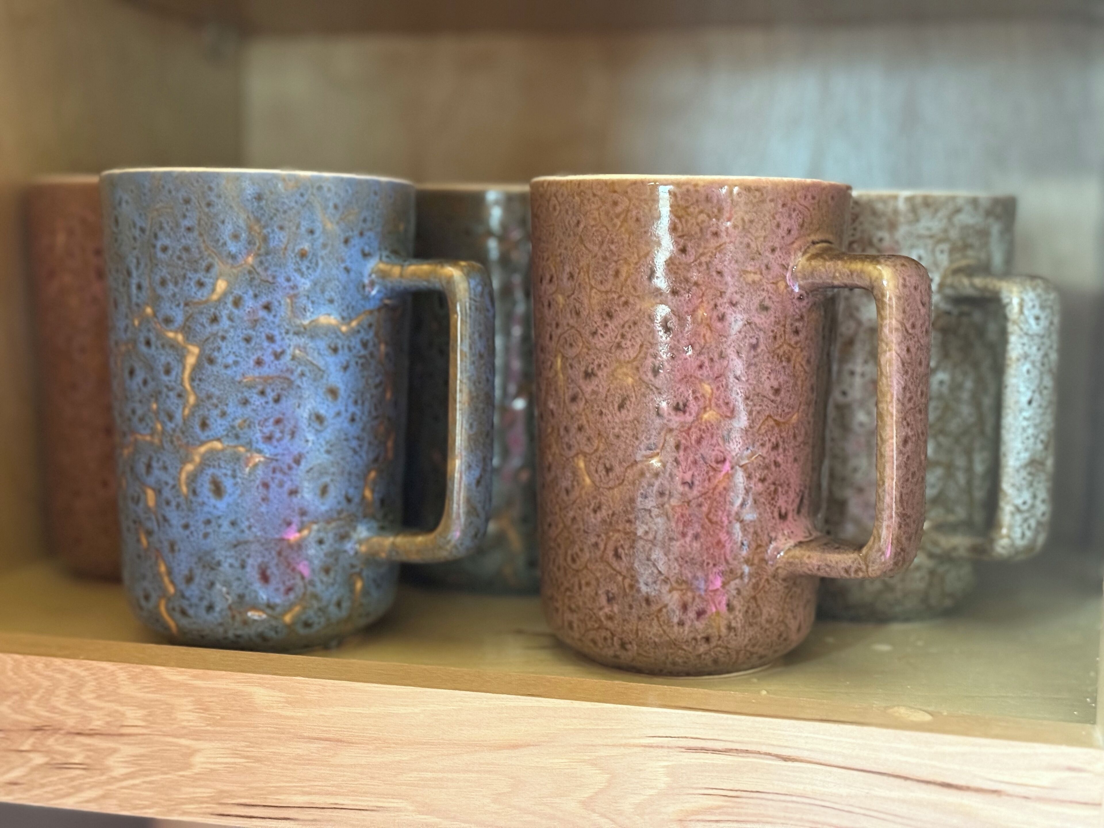 A shelf with ceramic mugs.