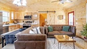 A wooden cabin interior with a kitchen, dining area, and living room.