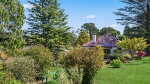 A house with a red roof, surrounded by lush greenery and trees. - The Outlook in Leura (Leura)