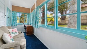 A sunroom with large windows, a blue carpet, and a wooden desk. - The Outlook in Leura (Leura)