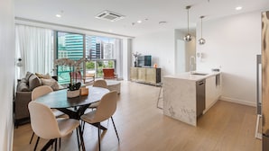 Un apartamento moderno con comedor, cocina y ventanas amplias con vista a la ciudad.
