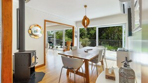 A spacious room with a large wooden table, a modern pendant light, and a view of the outdoors through large windows. - Spacious 3Br Mission Bay Home With Parking! (Auckland)