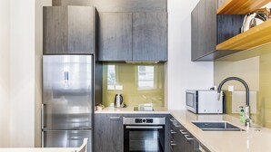 Una cocina moderna con electrodomésticos de acero inoxidable, armarios de madera y horno empotrado.