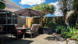Eine Terrasse im Freien mit Tisch und Stühlen, einer hängenden Pflanze und einem Holzzaun.