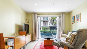 Una habitación de hotel moderna con comedor, sofá, televisor y vistas al exterior.