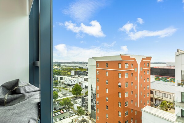 A high-rise building with a view of a cityscape through a window. - Zodiak Stays: Cozy CBD 2BR Near Top Dining Spots (Auckland)
