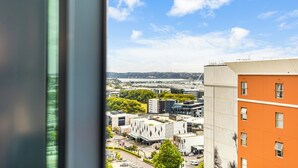 A cityscape with modern buildings, a clear blue sky, and a distant body of water. - Zodiak Stays: Cozy CBD 2BR Near Top Dining Spots (Auckland)