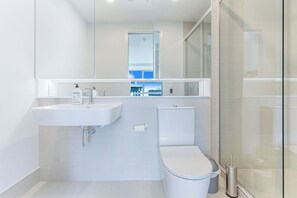 Un baño moderno con lavamanos, inodoro y cabina de ducha de vidrio.