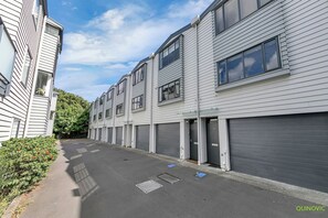 Een rij moderne, meerlaagse woongebouwen met grijze bekleding en grote ramen.
