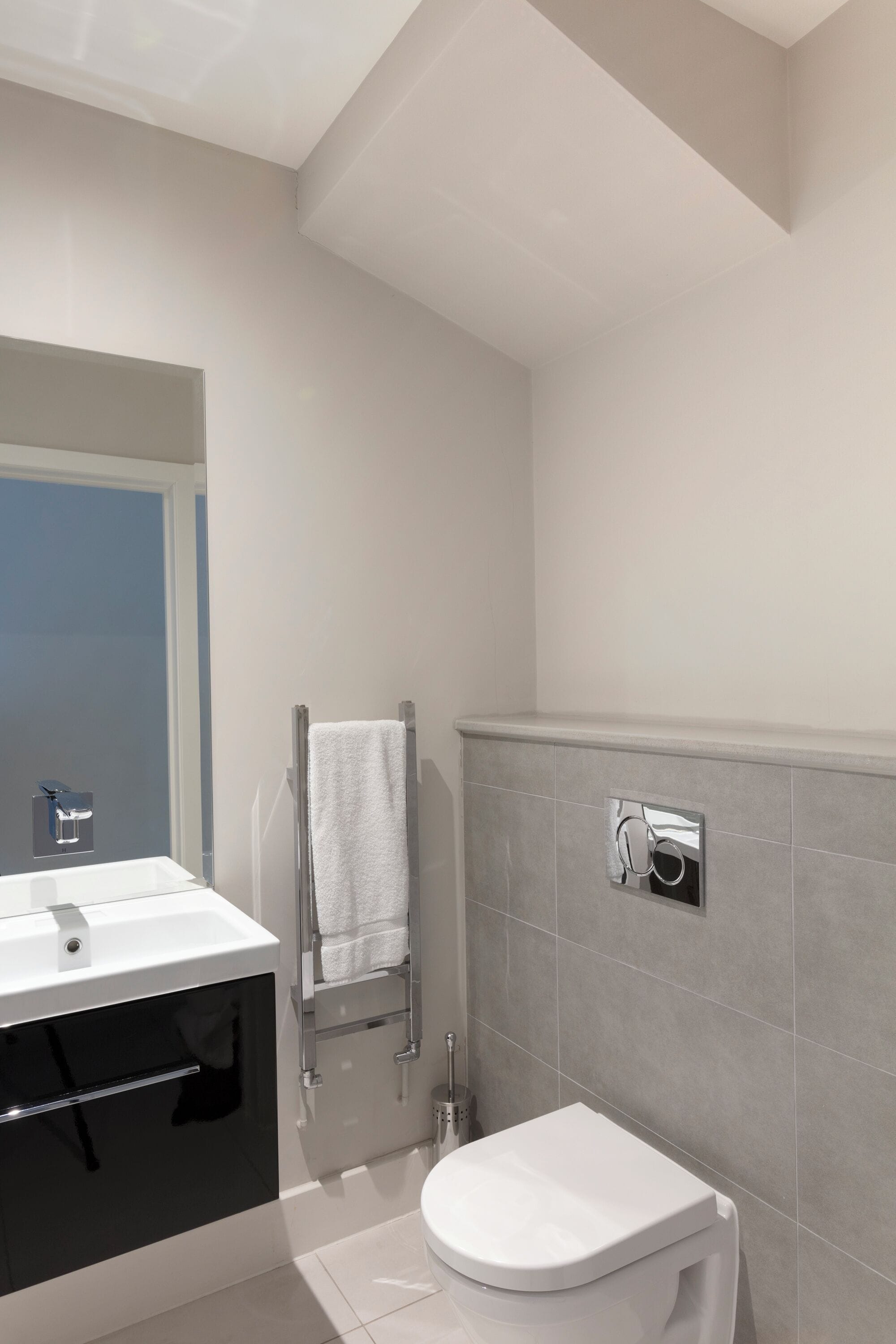 Une salle de bain moderne avec un lavabo blanc, des toilettes et un porte-serviettes.