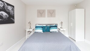Une chambre à coucher comprenant un lit, deux tables de chevet, une armoire et des œuvres d’art murales.