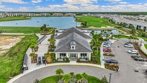 A hotel with a central building, a parking lot, a golf course, and a body of water. - Cozy 2-bedroom condo with WiFi, fitness room in charming Babcock Ranch Florida.  (Punta Gorda)