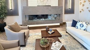 A modern living room with a fireplace, a sofa, a coffee table, and a decorative wall. - Cozy 2-bedroom condo with WiFi, fitness room in charming Babcock Ranch Florida.  (Punta Gorda)